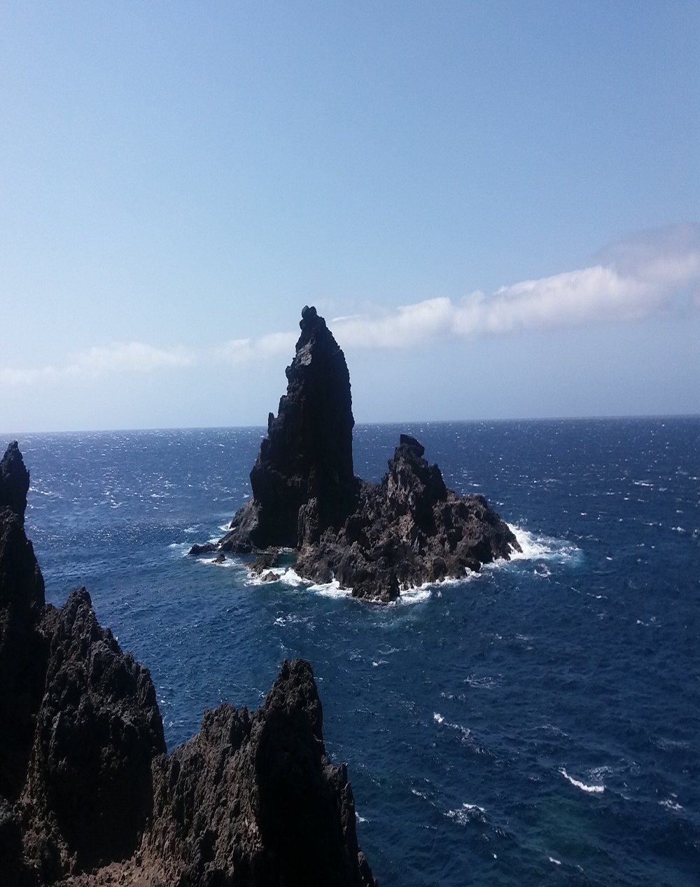 Panorámica de una escultura natural de lava volcánica. Imponente solitaria acariciada por el viento, mojada por la sal.
