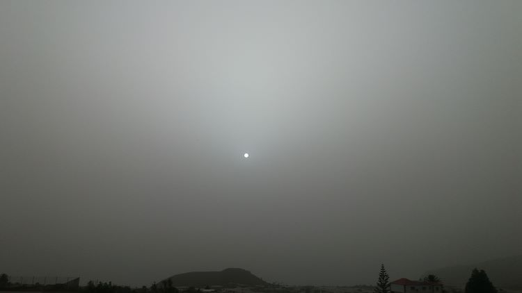 Sol blanco de calima; de espejo de polvo del desierto.