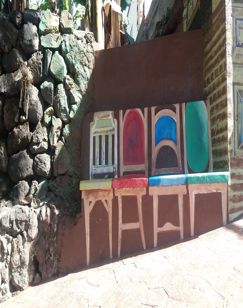 Se ve unas sillas pintadas en un banco de piedra. Un domingo, dominguero.