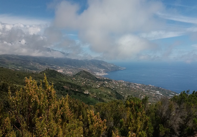 Se ve la zona este de la isla de la palma: las breñas, santa cruz de la palma. Entre brezos y nubes de colores azules y blancas