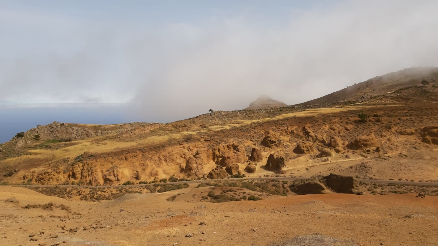 Se ve un paisaje casi lunar de colores amarillos, por encima de las nubes y del mar