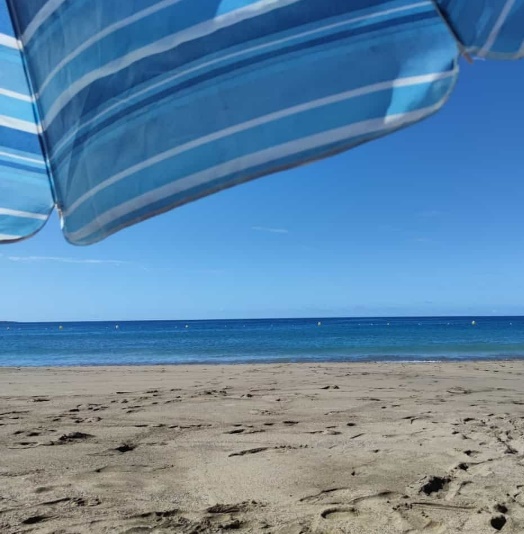 Se ve una playa de arena blanca, y el azul profundo del mar. Las huellas dejadas en el pasear.