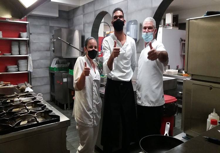 Se ven tres cocineros entusiasmados por un gracias por haber comido sus deliciosos platos de comida