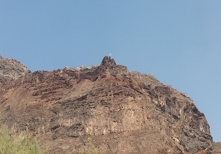 Se ve un risco y la luna apareciendo por el centro de el. Impresionante conjunción paisajística.